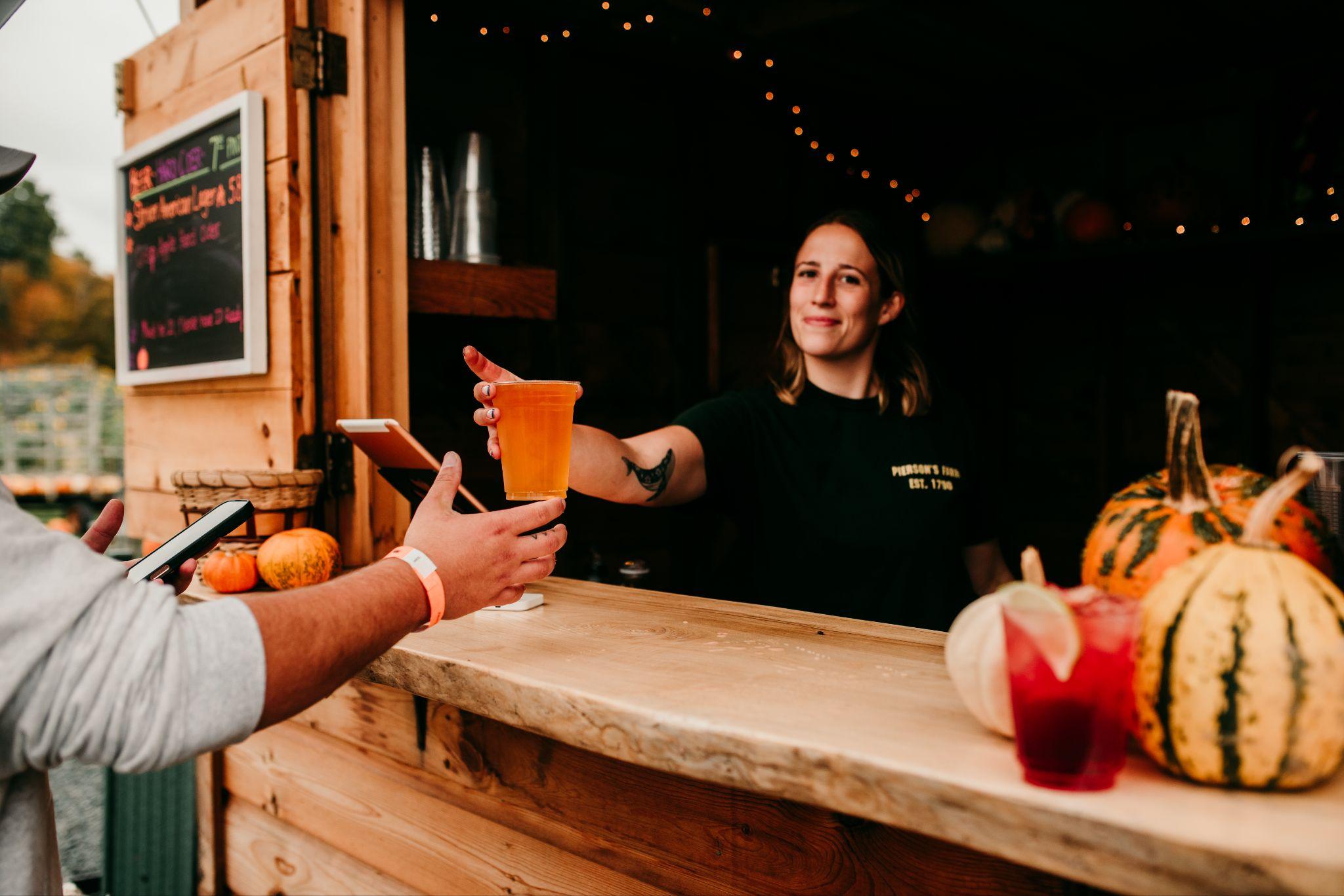 A drink being handed over the counter at the beer and cider shed